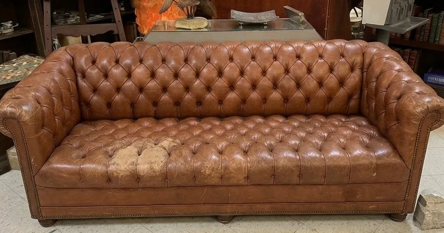 Tan Chesterfield sofa with worn, discoloured seat before restoration